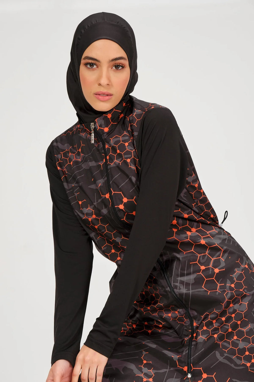 Close-up of model wearing orange and black patterned burkini top and hijab.