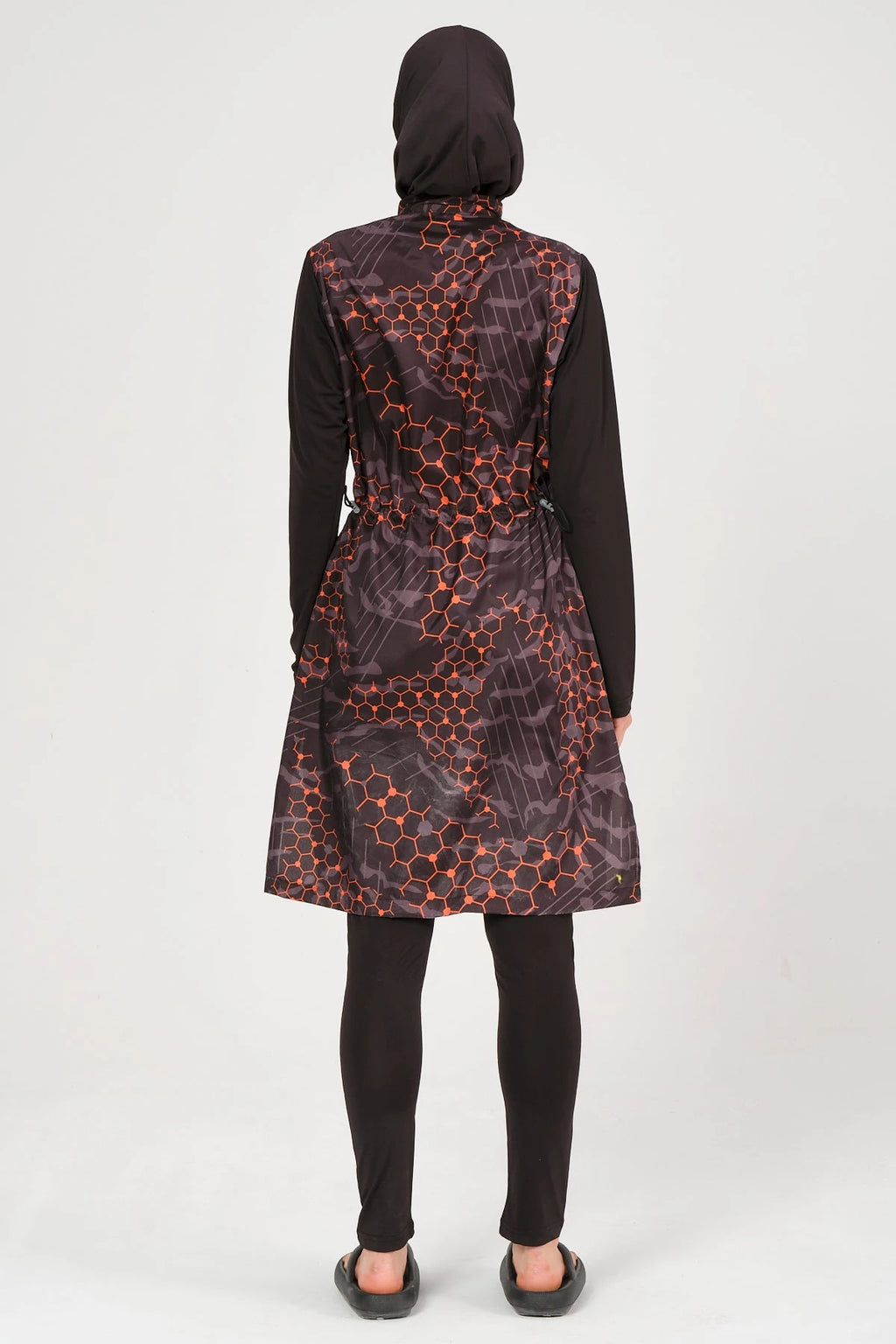 Model in orange and black patterned burkini set, back view, full coverage.