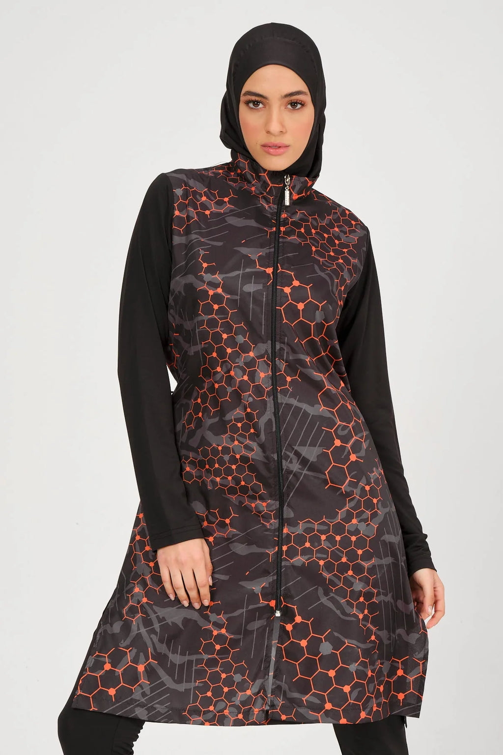 Model in orange and black patterned burkini set, front view, confident pose.