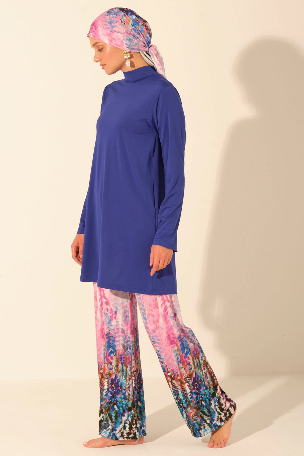 Woman in full coverage burkini set walking, side view.