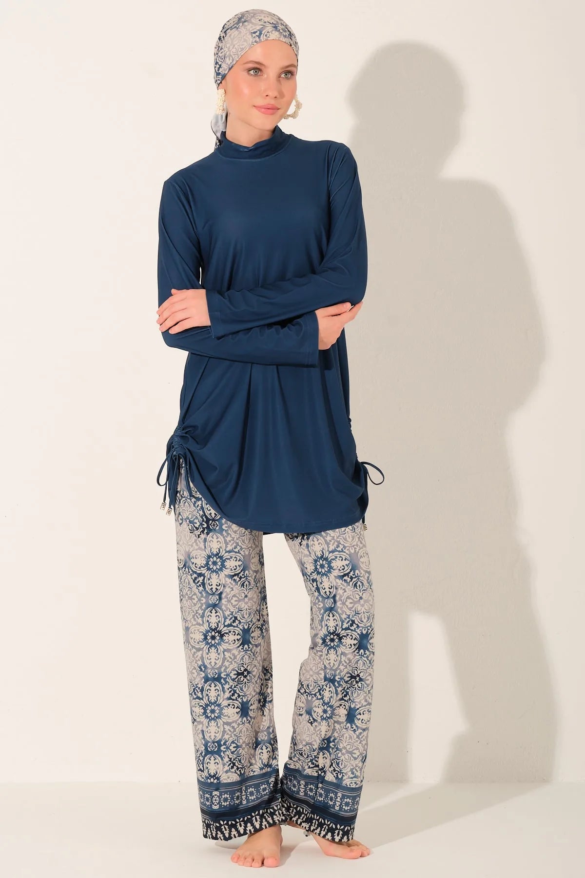 Blue burkini top and patterned swim pants with crossed arms.