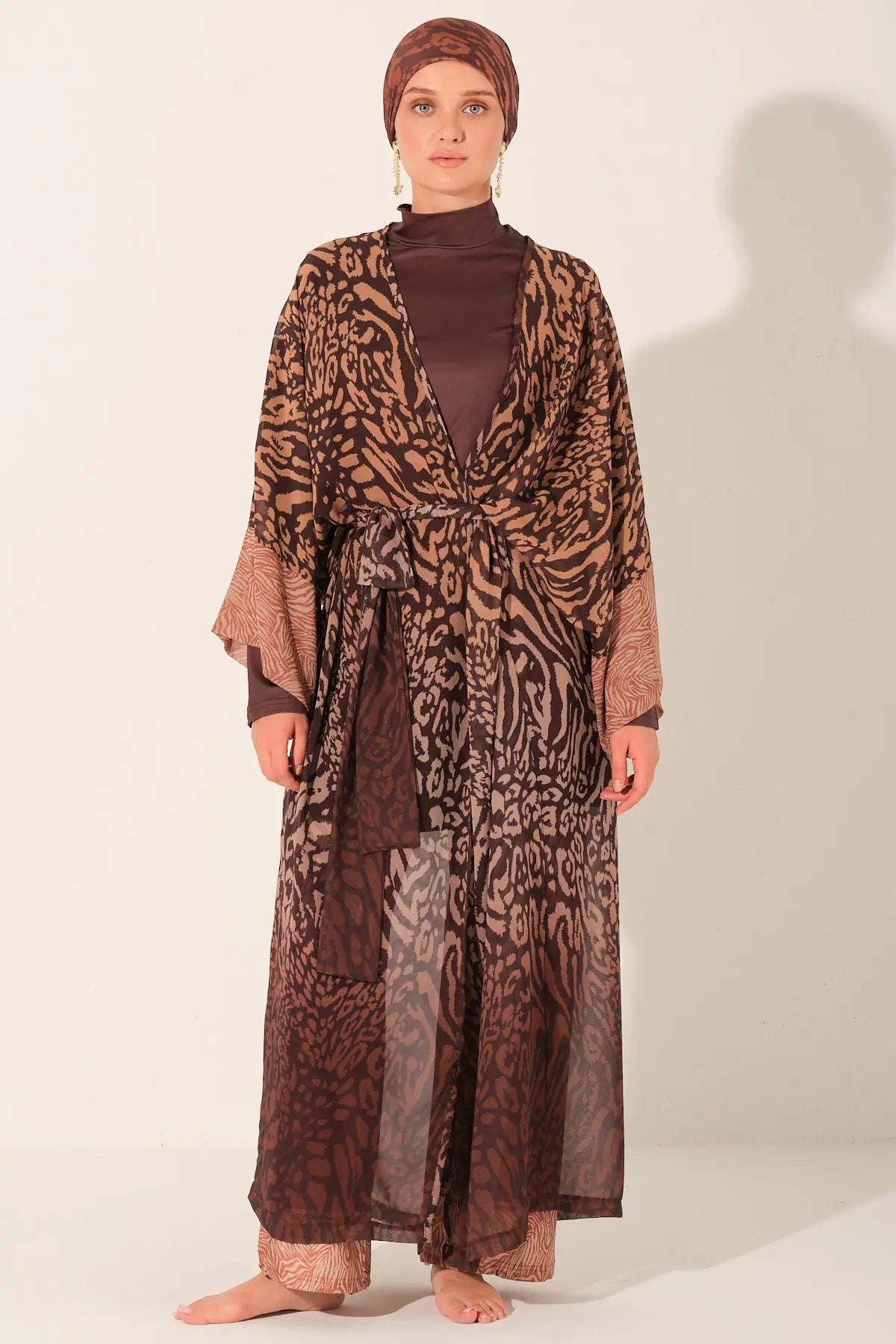 Person wearing a long, patterned dress with a matching headscarf on a white background