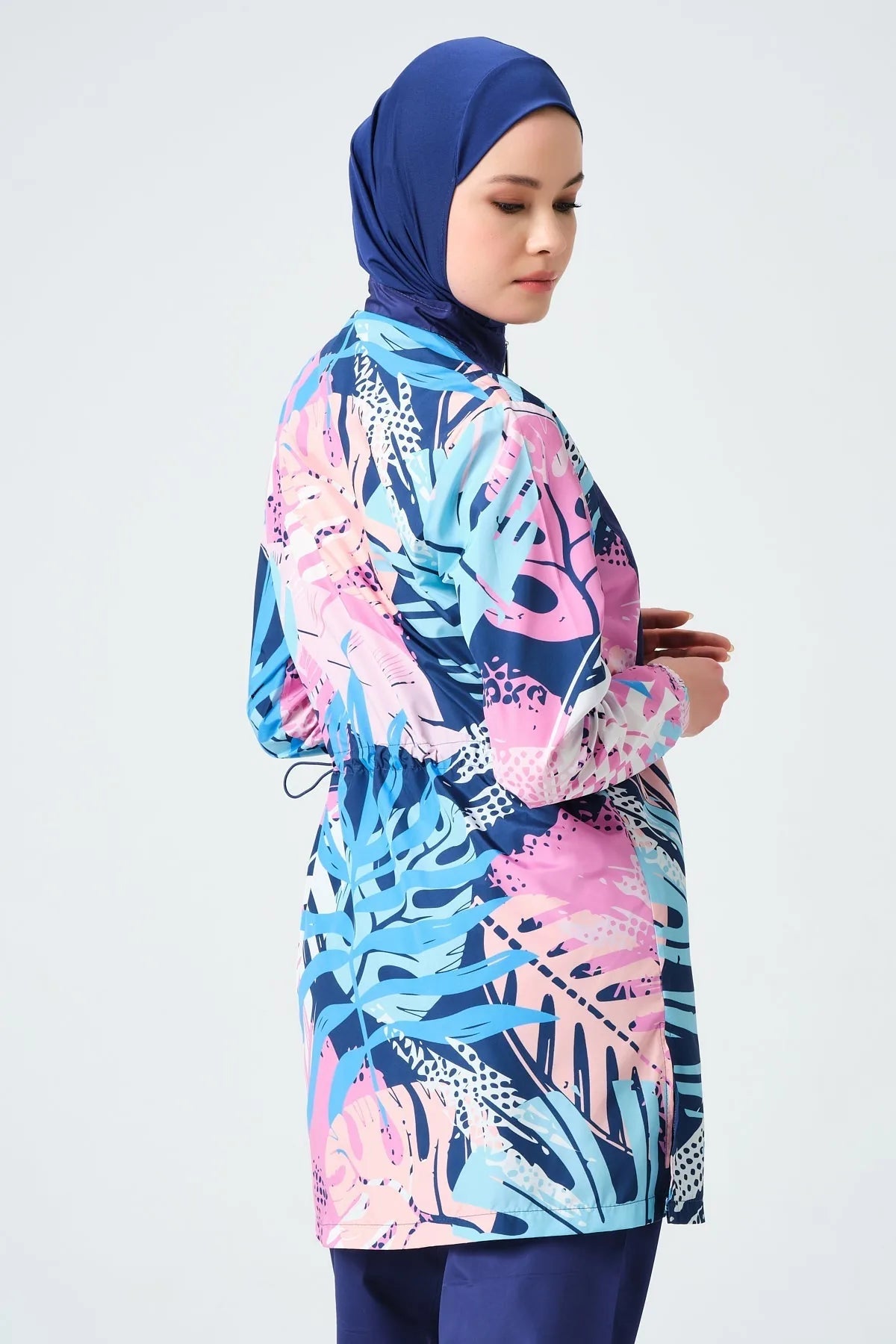 Side profile of model wearing tropical print burkini top with drawstring detail.