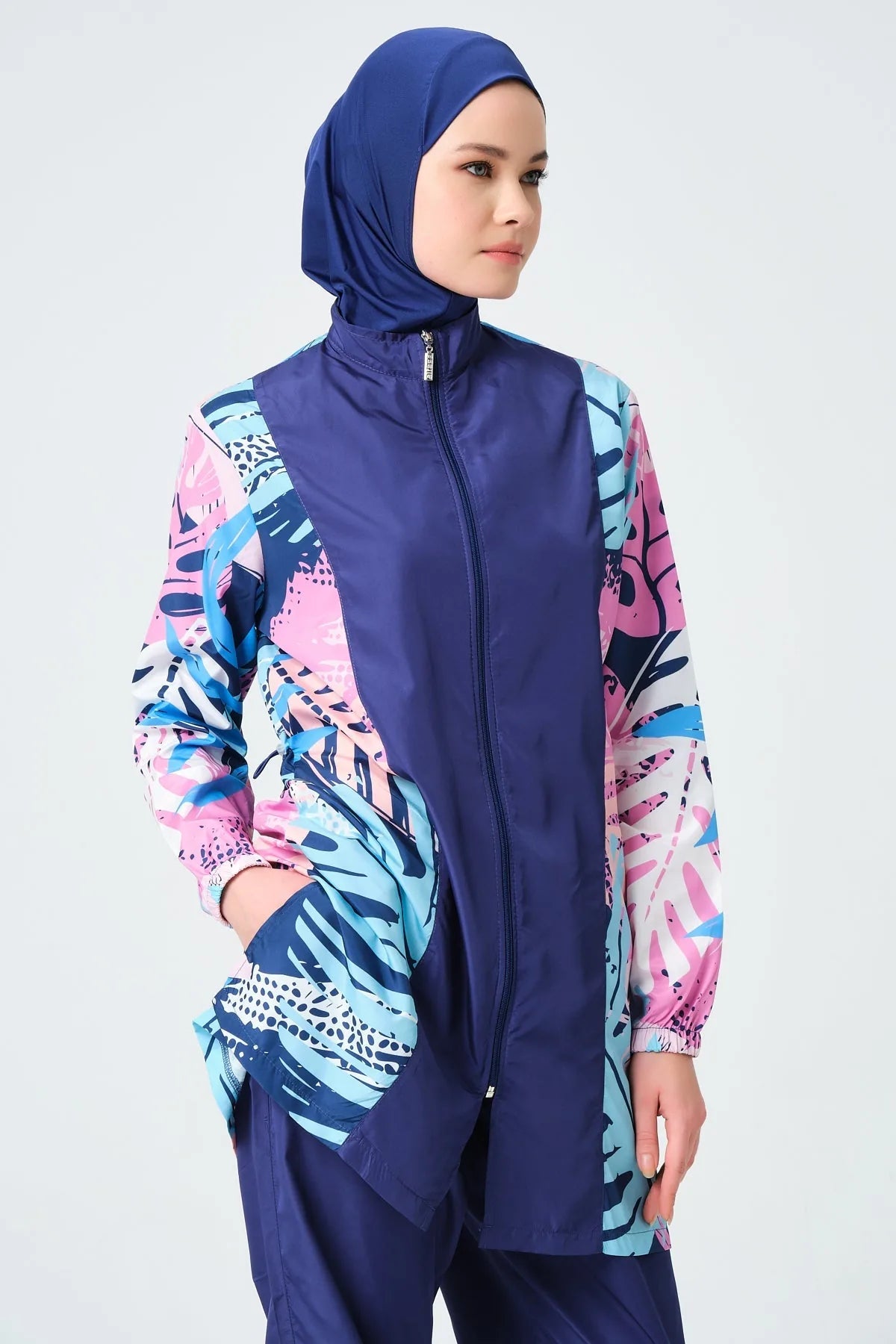 Model in tropical print burkini showing front zipper pockets.