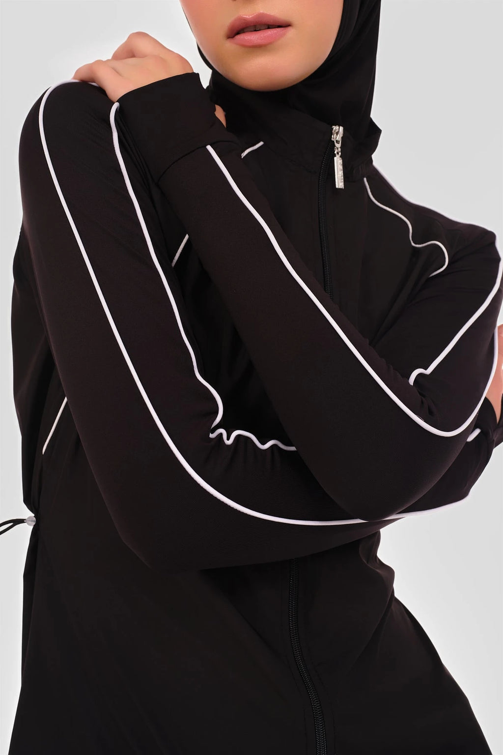 Close-up of black burkini top with white piping detail on sleeve.