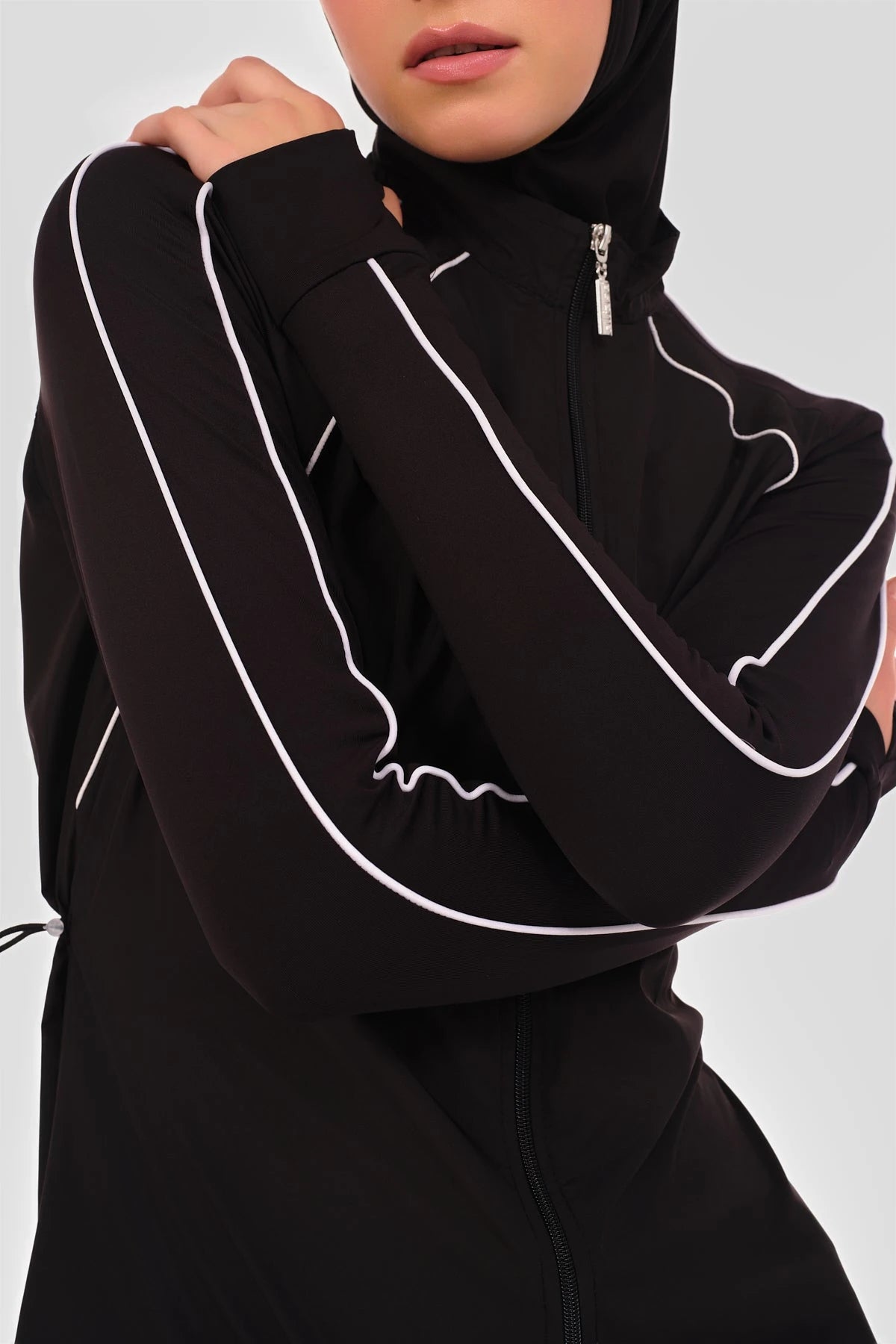 Close-up of black burkini top with white piping detail on sleeve.