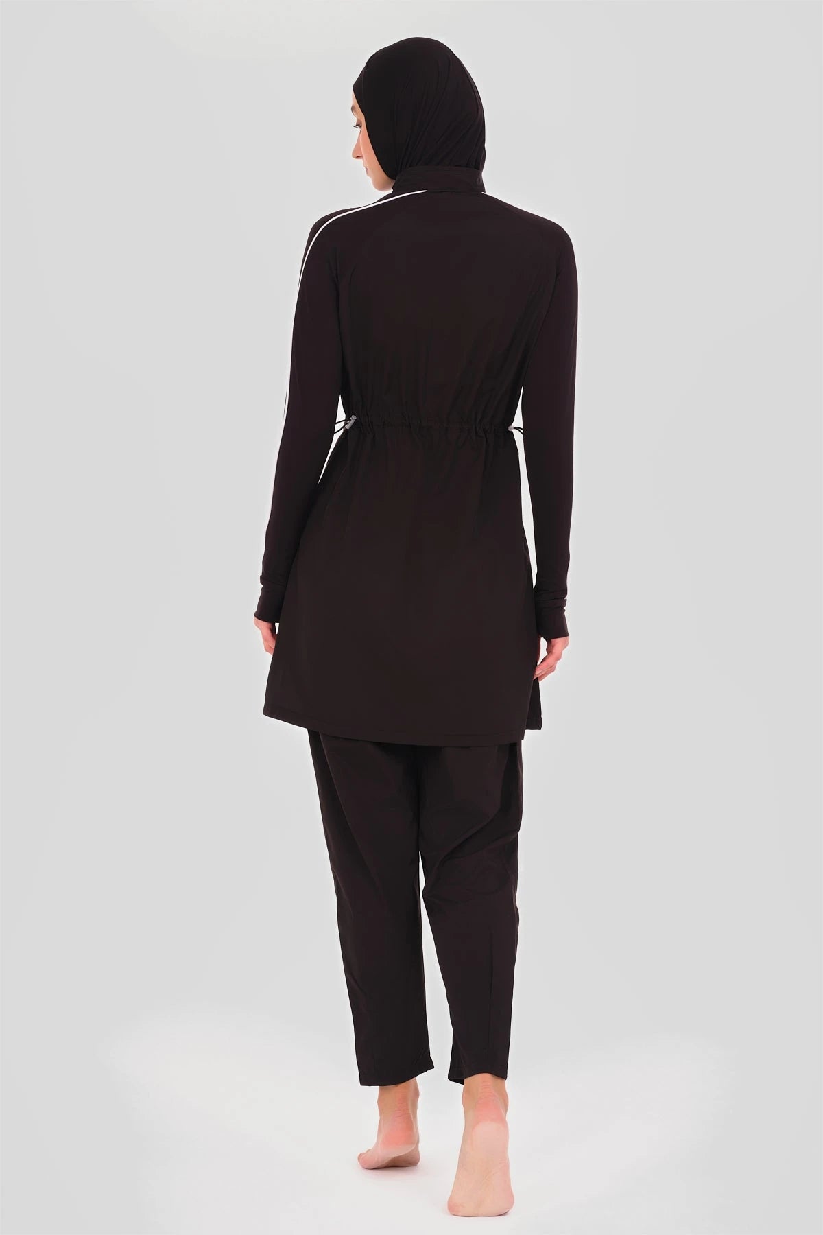 Black sporty burkini with white piping, back view on plain background.