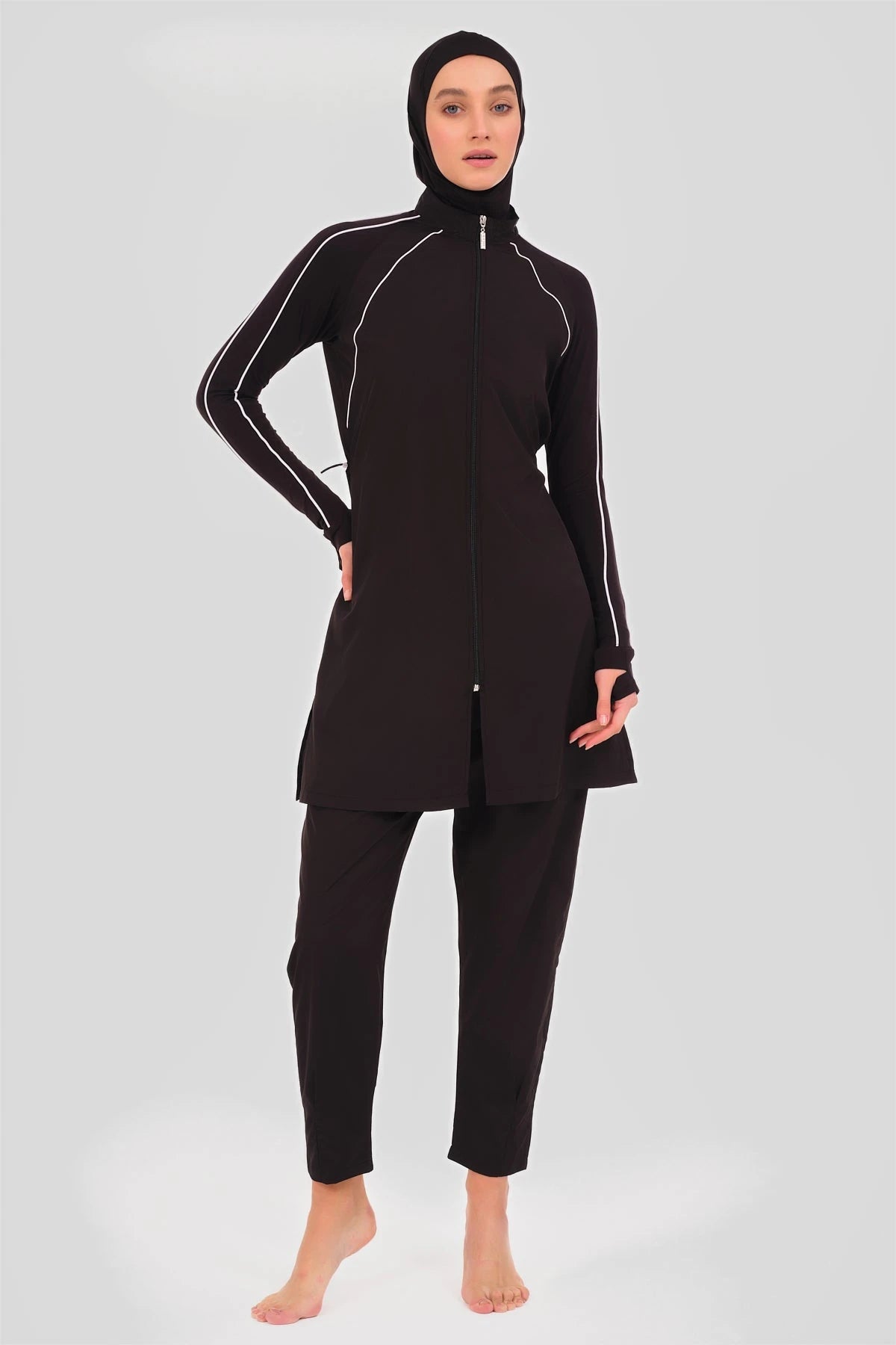 Model in black sporty burkini with white piping, front pose.