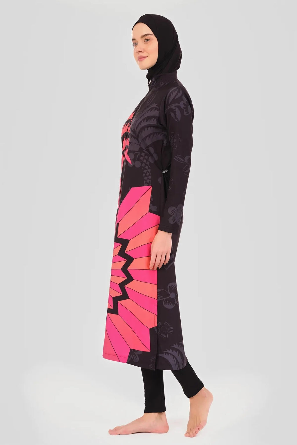 Side view of a woman in a fuchsia graphic print burkini showing the full length.