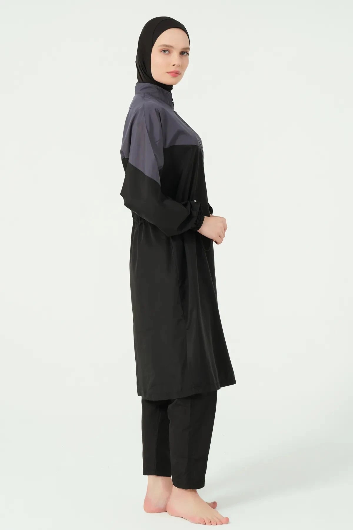 Side view of a woman wearing a monochrome burkini set with side slits.