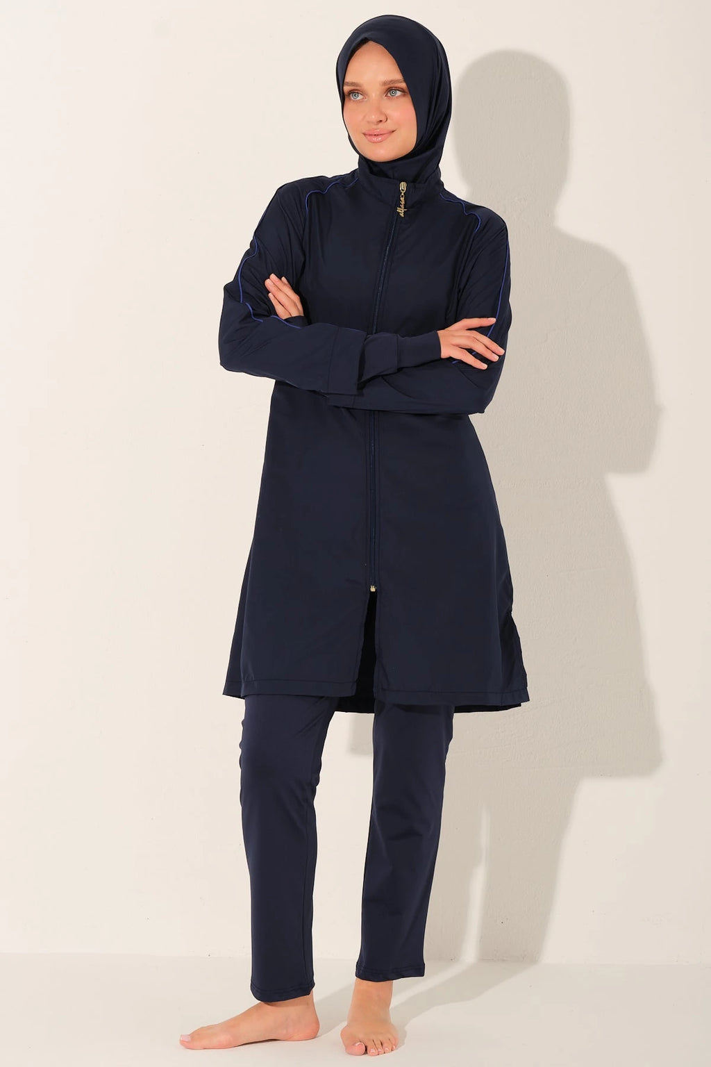 Model in navy burkini set with arms crossed, full length.