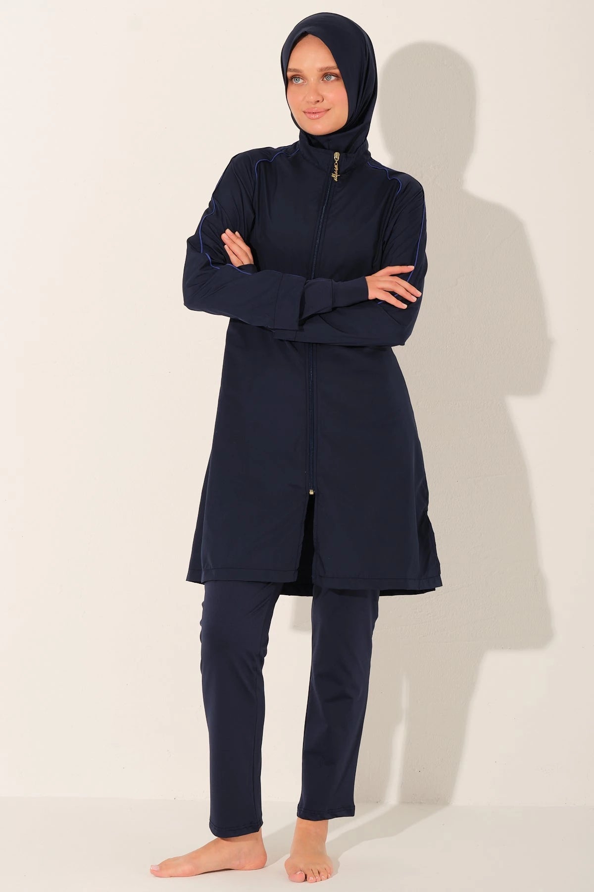 Model in navy burkini set with arms crossed, full length.