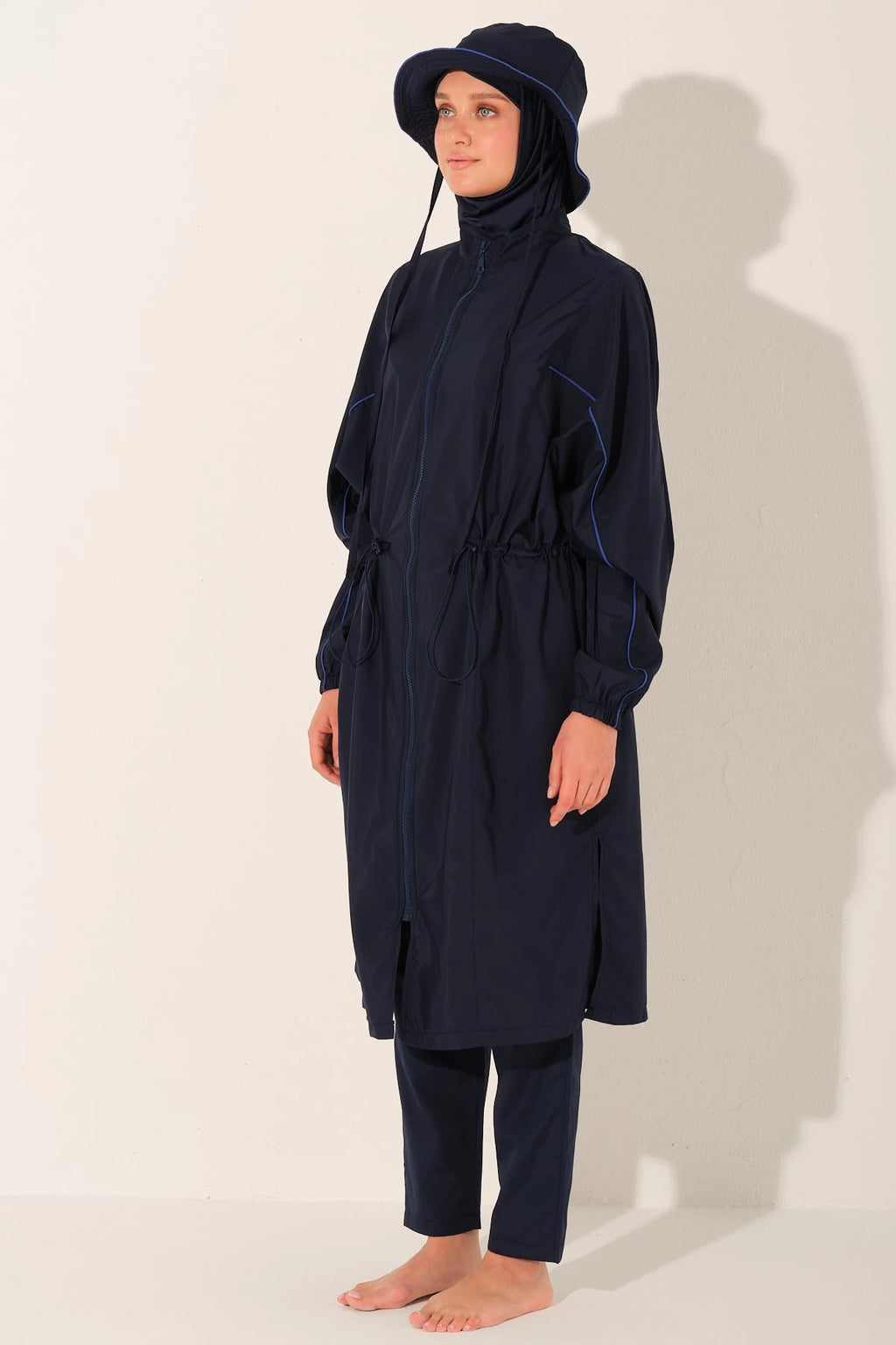 Woman in navy trek burkini set with hat, right side view.
