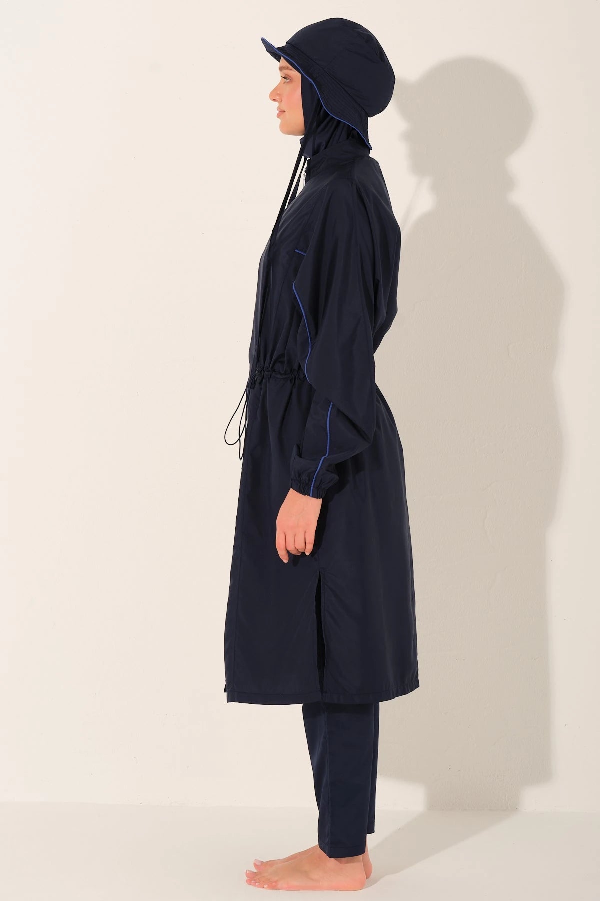 Woman in navy trek burkini set with hat, left side view.