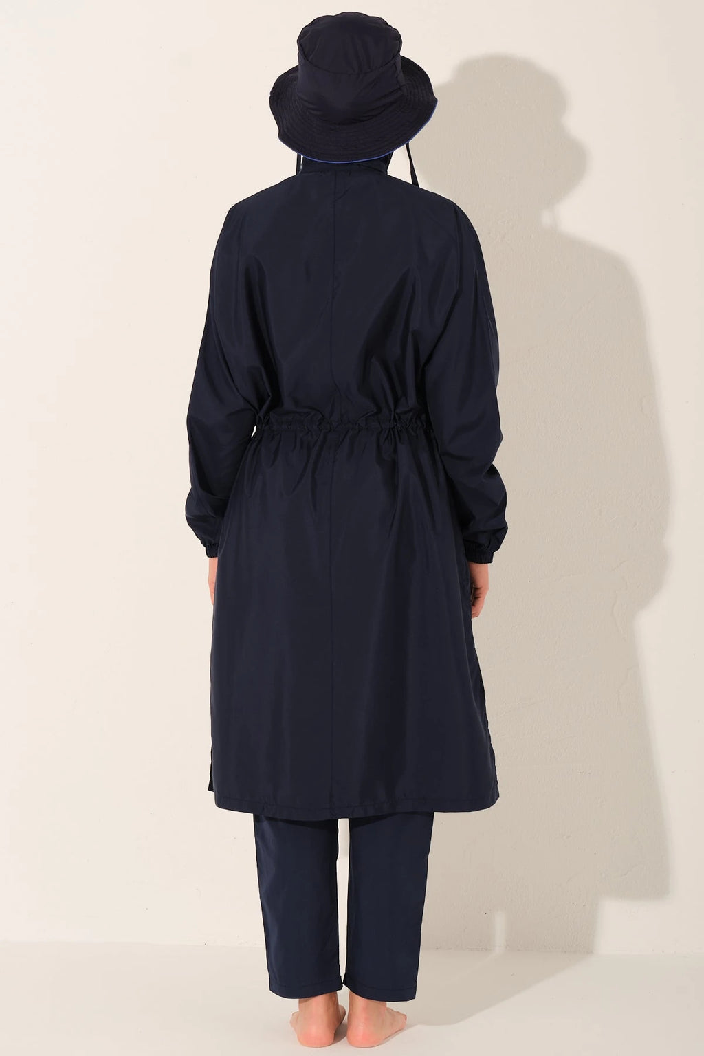 Woman in navy trek burkini set with hat, back view.