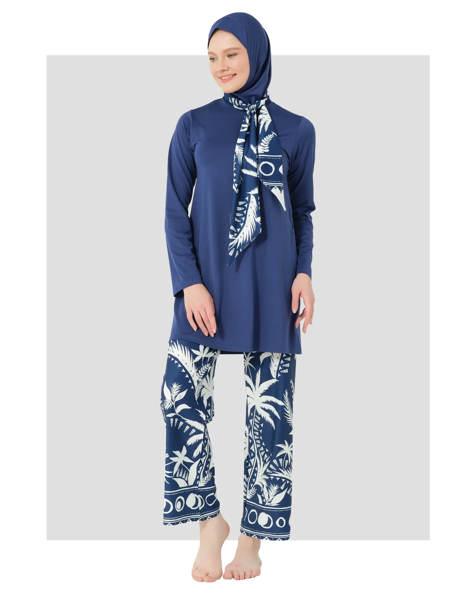 Woman in navy Lycra burkini with white palm print pants, front view.