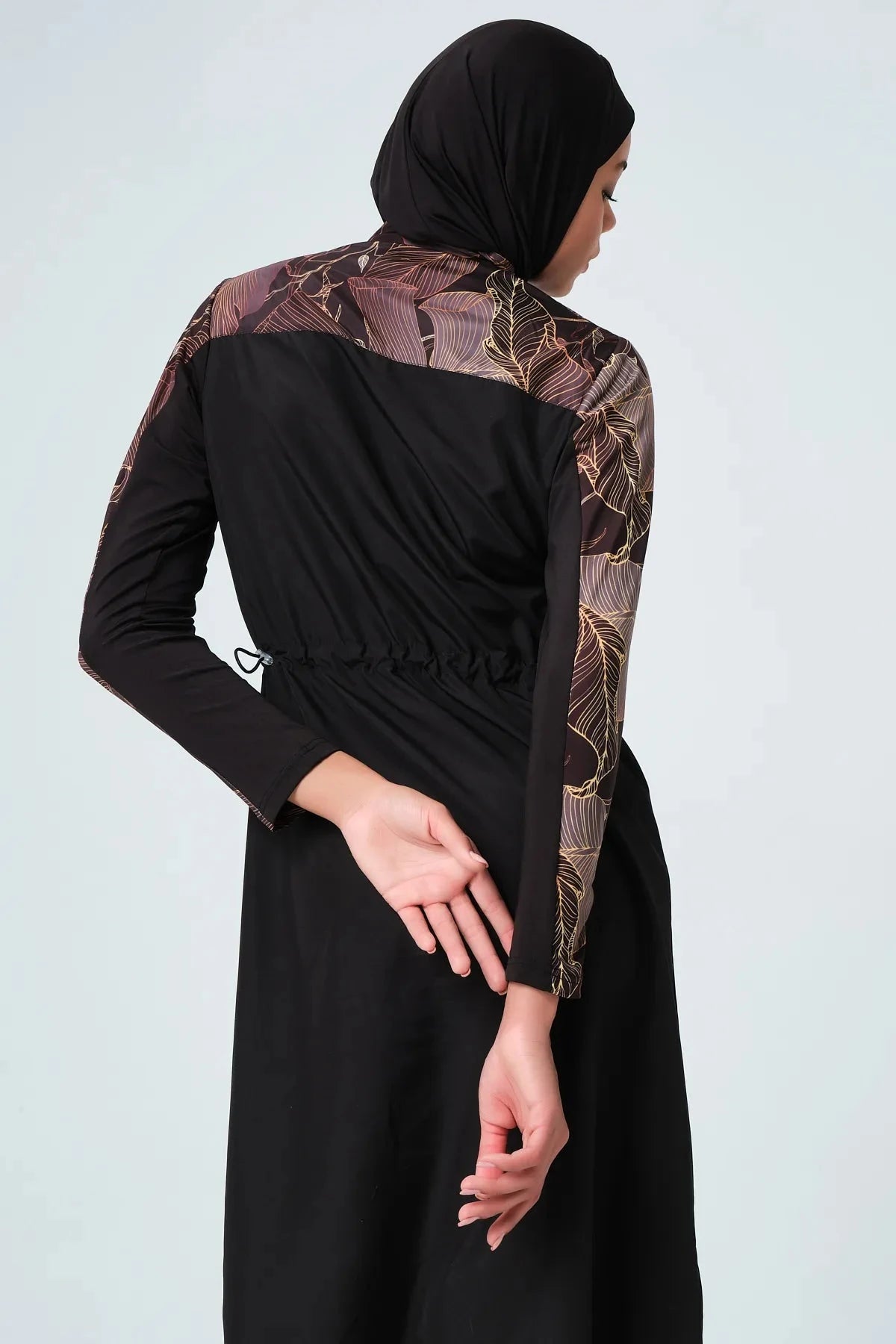 Back detail of black burkini with patterned sleeves and drawstring waist.