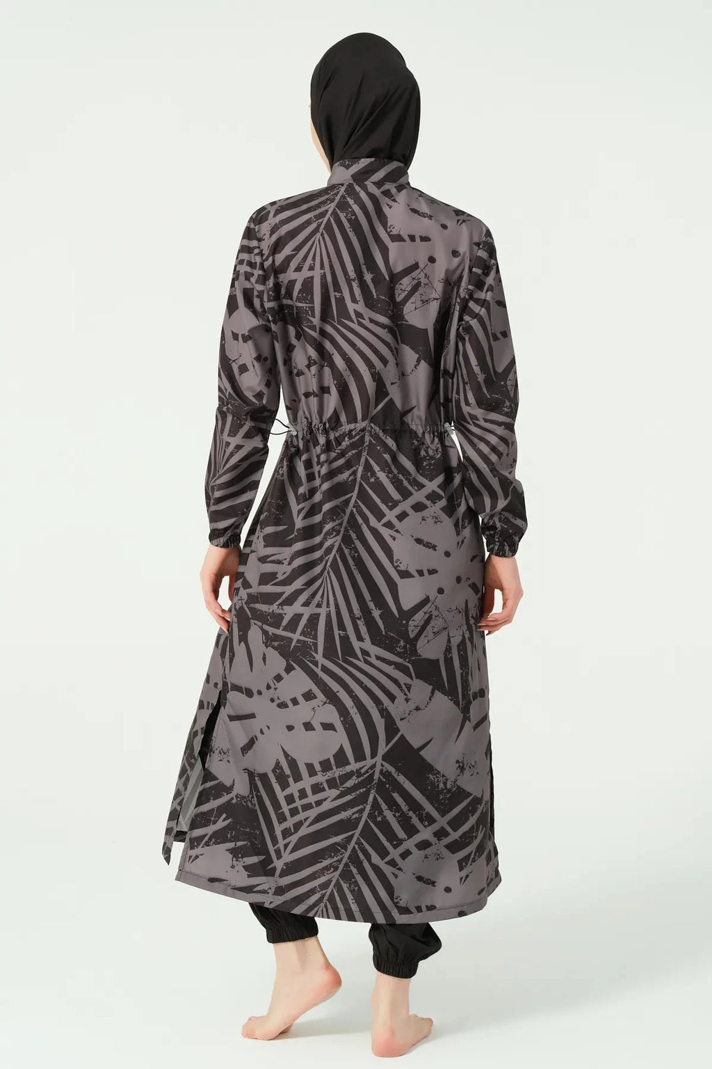 Back view of a woman in a black and grey abstract print burkini with drawstring.