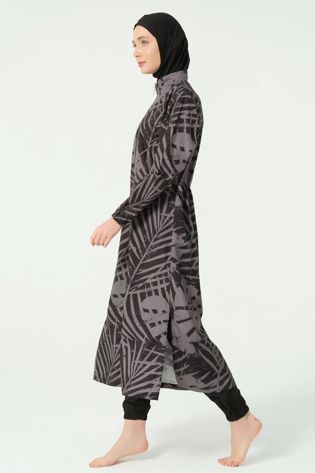 Side view of a woman wearing a black and grey abstract print burkini.