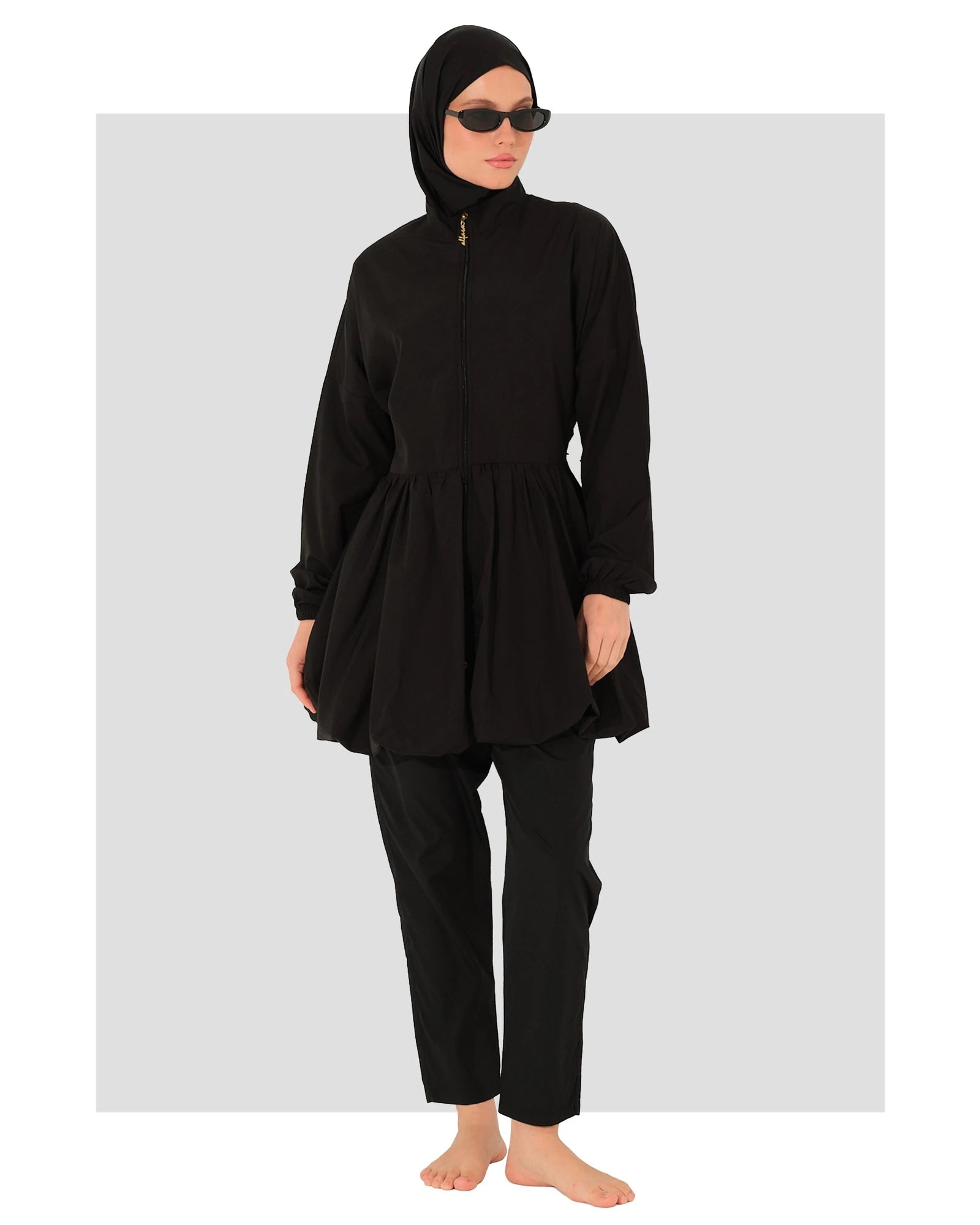 Model in black burkini swimsuit with sunglasses, front view.