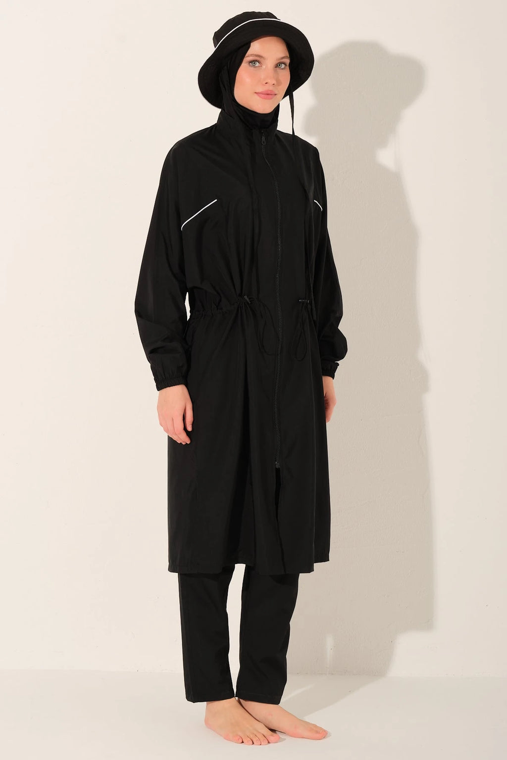 Black burkini set with long top, swim pants, and bucket hat angled view.