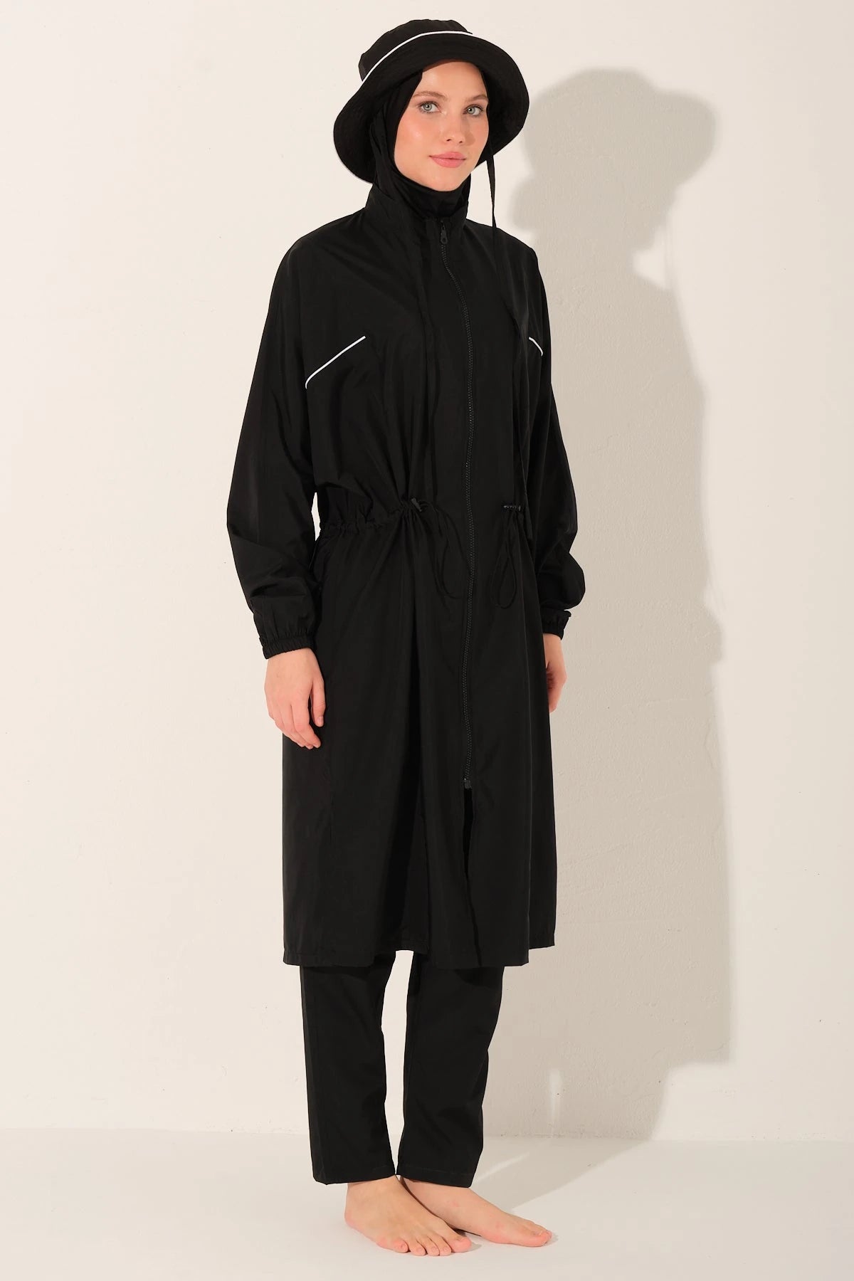 Black burkini set with long top, swim pants, and bucket hat angled view.