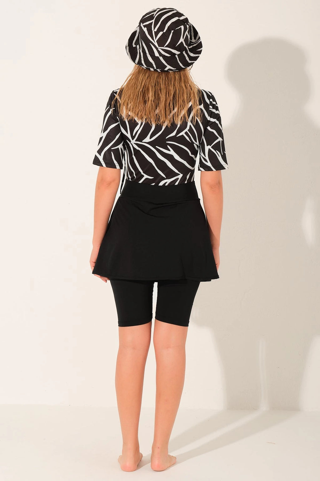 Woman in monochrome sport burkini set with bucket hat, back view.