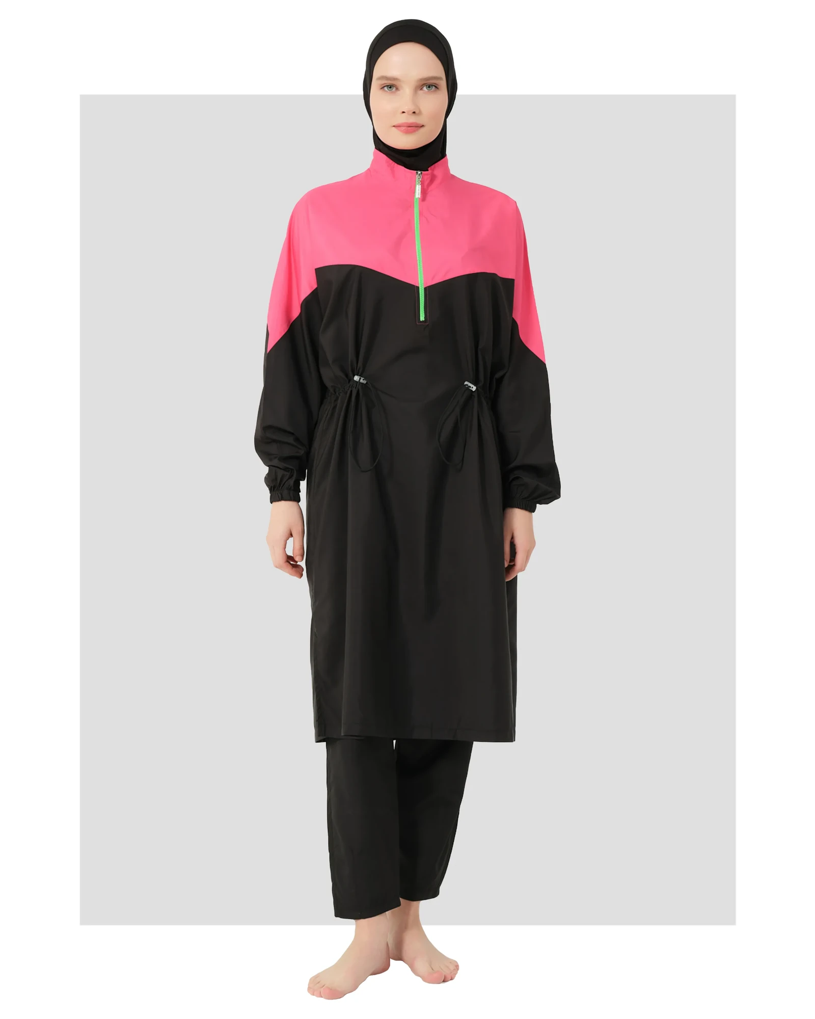Woman wearing a black and fuchsia burkini with a half-zip high neck and adjustable waist.