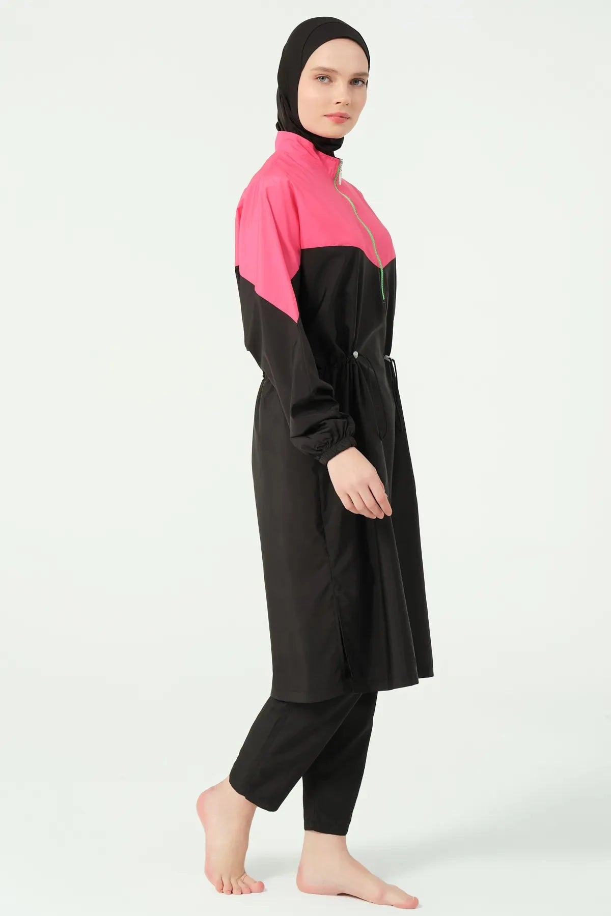 Side view of a woman in a black and fuchsia burkini with a relaxed-fit tunic and pants.