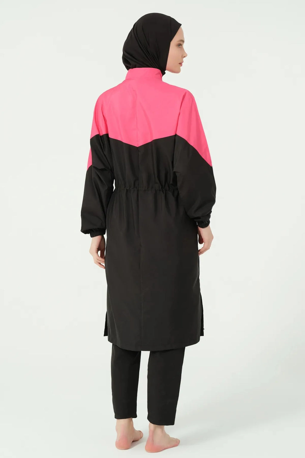 Back view of a woman in a black and fuchsia burkini showing the tunic length and side slits.