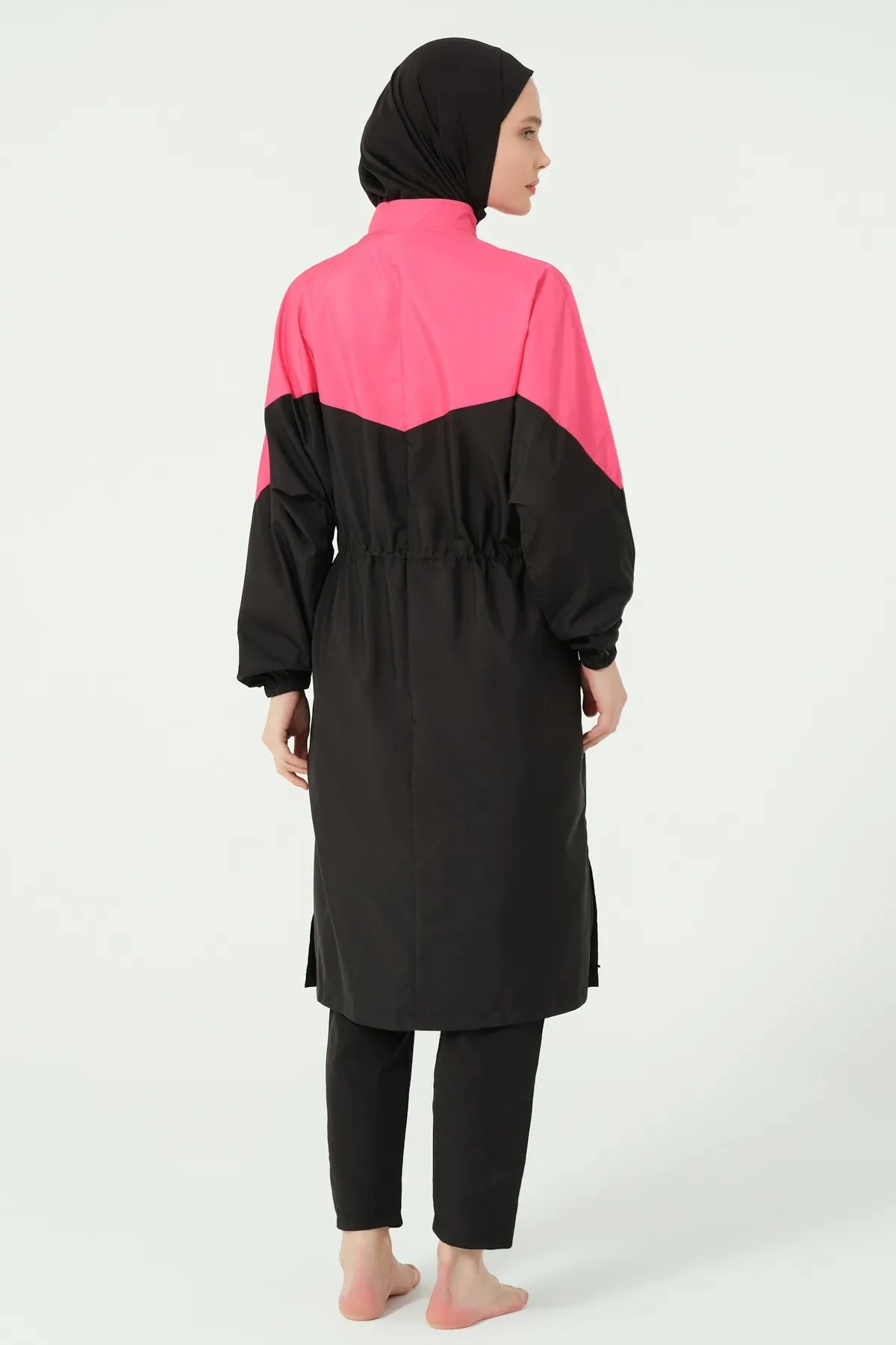 Back view of a woman in a black and fuchsia burkini showing the tunic length and side slits.