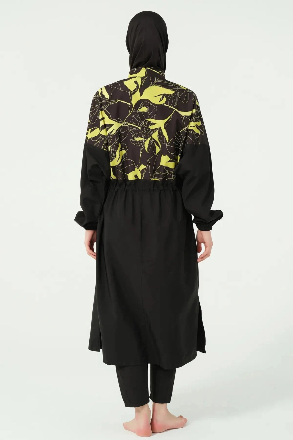 Woman wearing a black and yellow tropical print burkini set from the back.