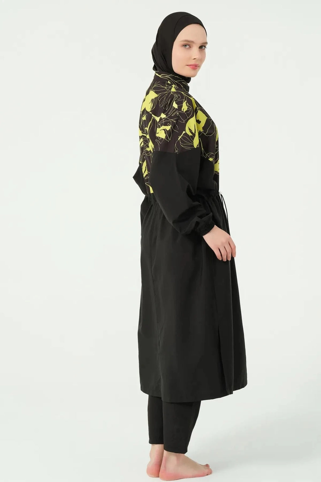 Woman wearing a black and yellow tropical print burkini set from the side.