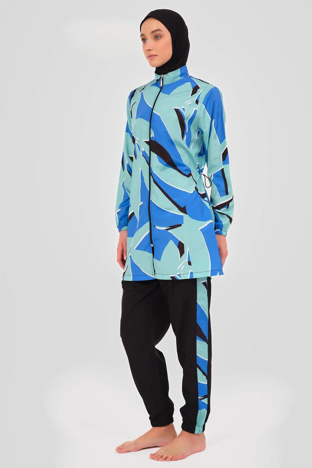 Woman in abstract print burkini set, side view, black hijab.