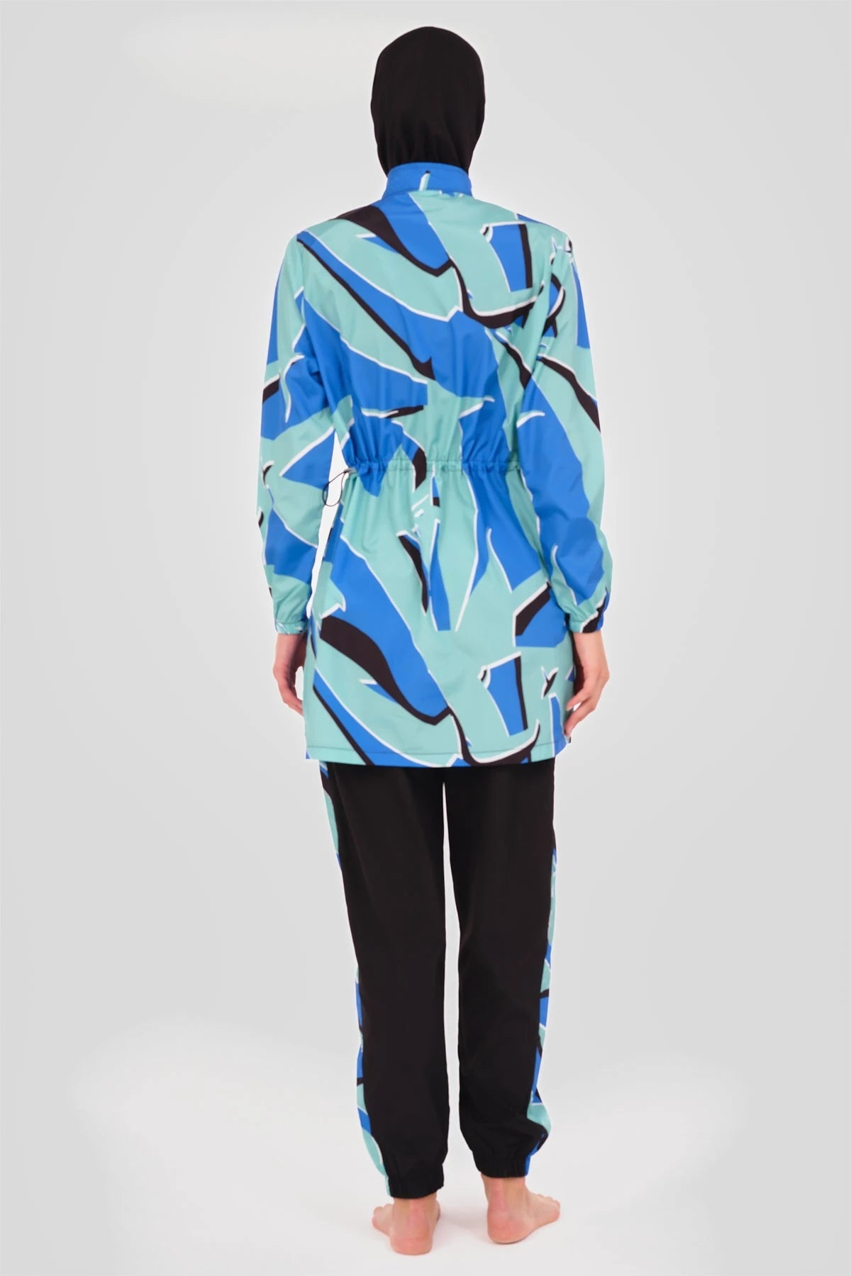 Woman in abstract print burkini set, back view, black hijab.