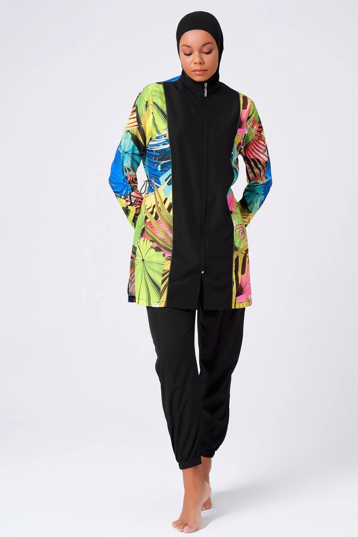 Woman in tropical print burkini with black hijab, full front view.