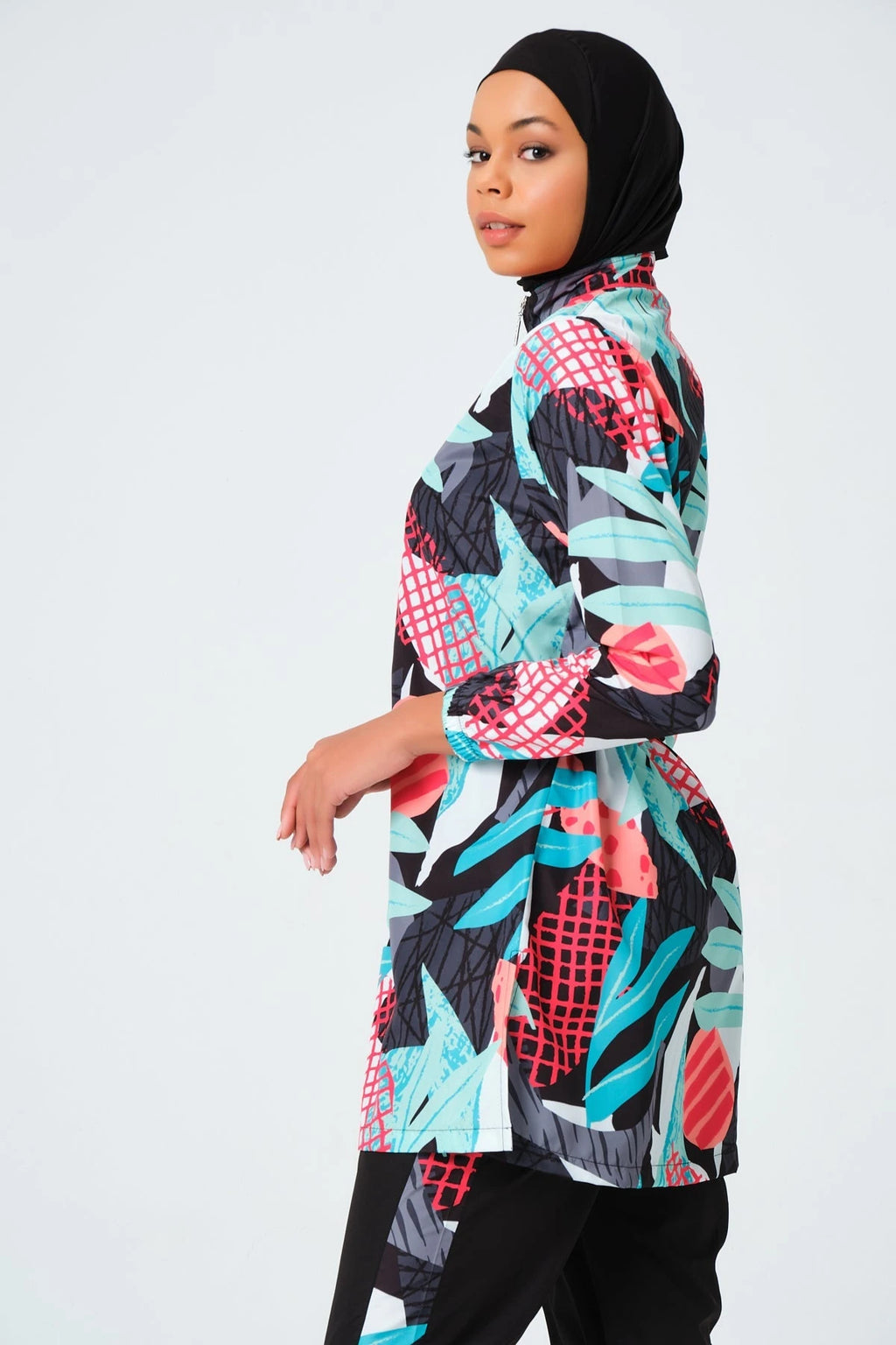 Woman in tropical print burkini set looking at camera from side.