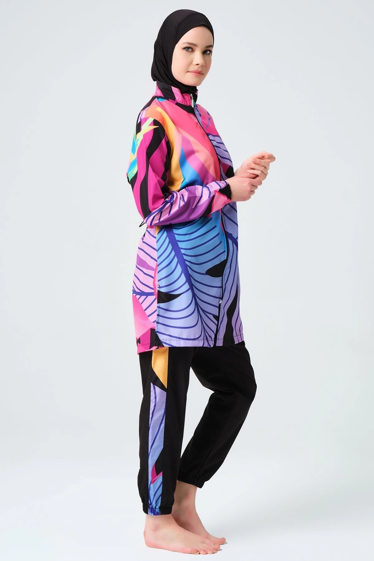 Model in vibrant tropical print burkini, side profile, black hijab.
