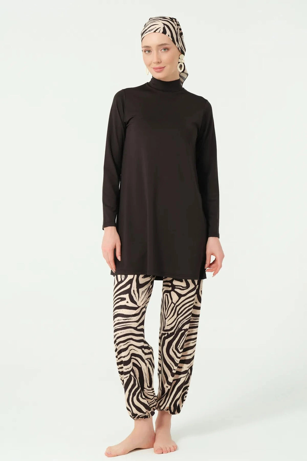 Front view of woman wearing black burkini top and zebra print swim pants.