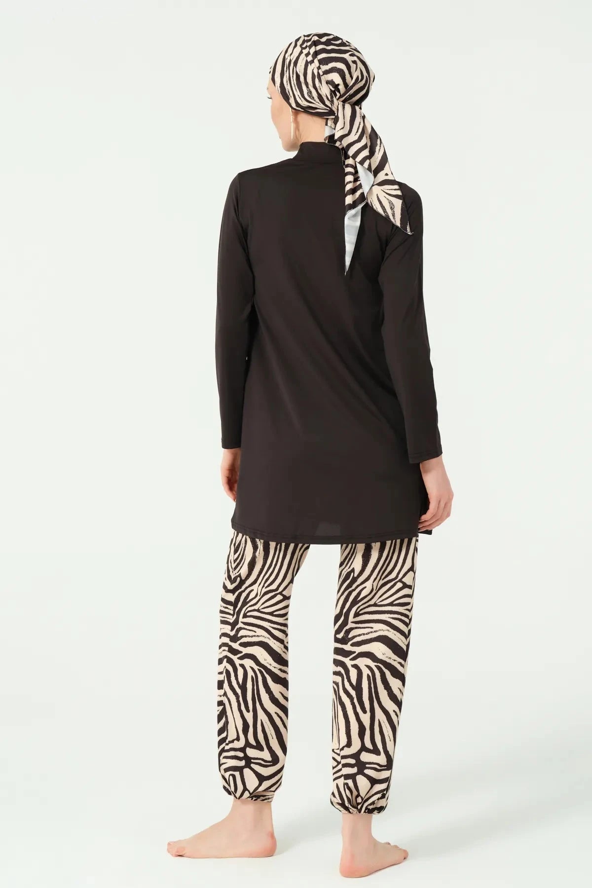 Back view of woman in full coverage black and zebra print burkini.