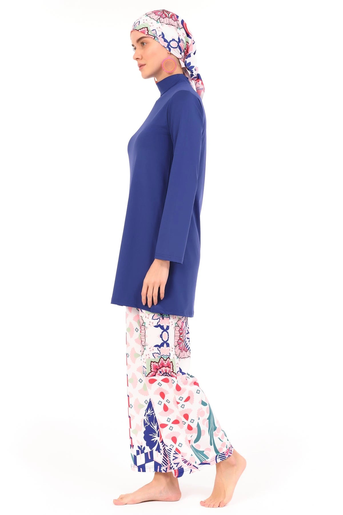 Model in blue and patterned burkini set, side view, walking on white background.