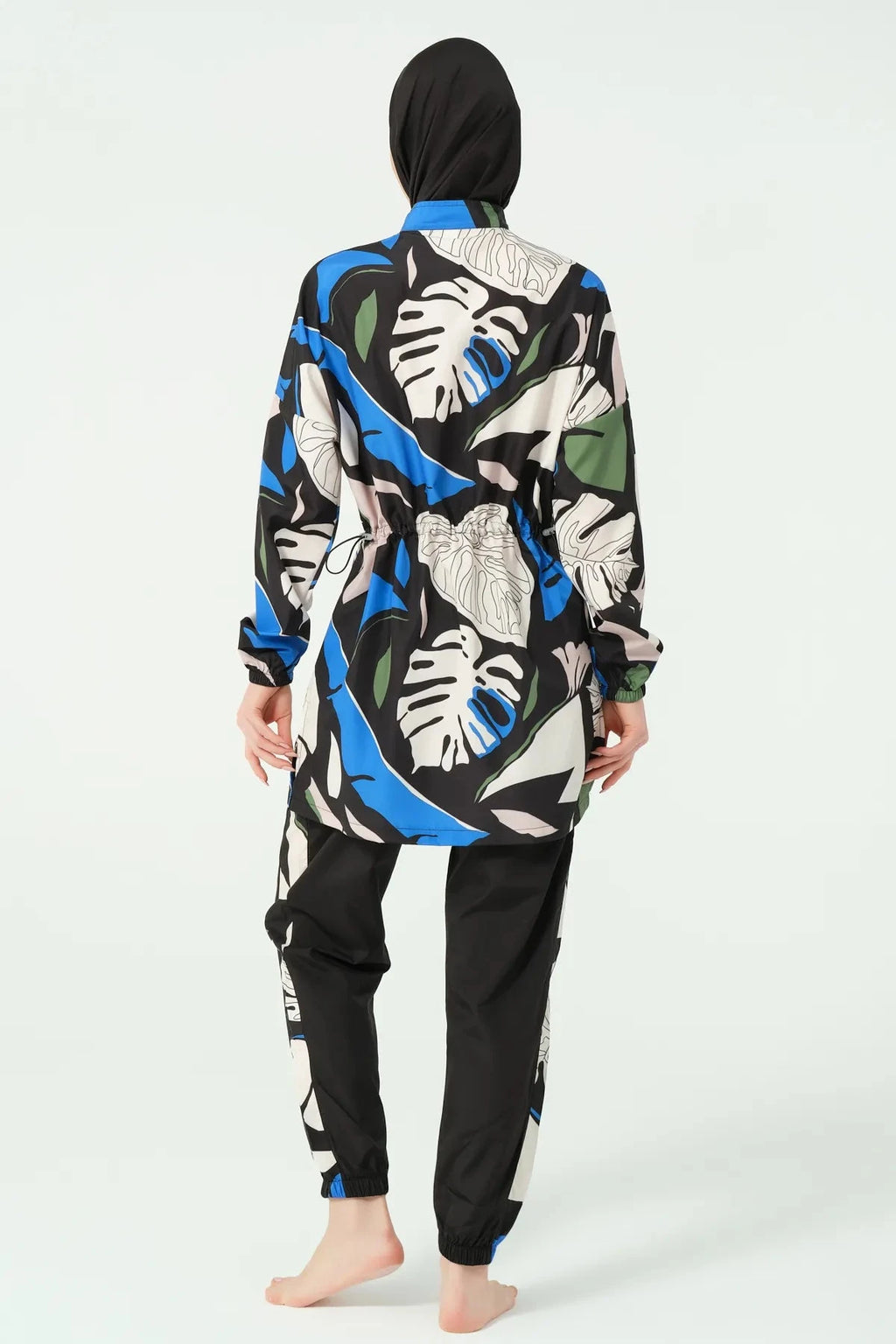 Woman wearing abstract print burkini set with black hijab, back view.