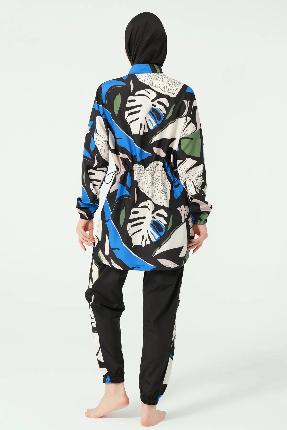 Woman wearing abstract print burkini set with black hijab, back view.