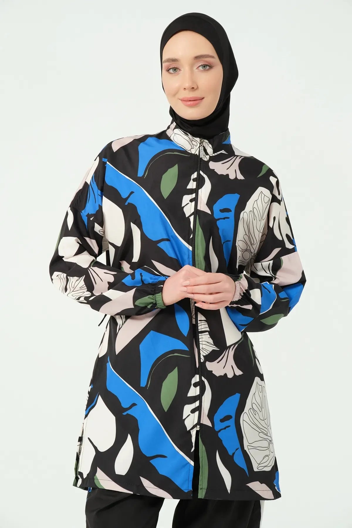 Woman in abstract print burkini top and black hijab, upper body front.