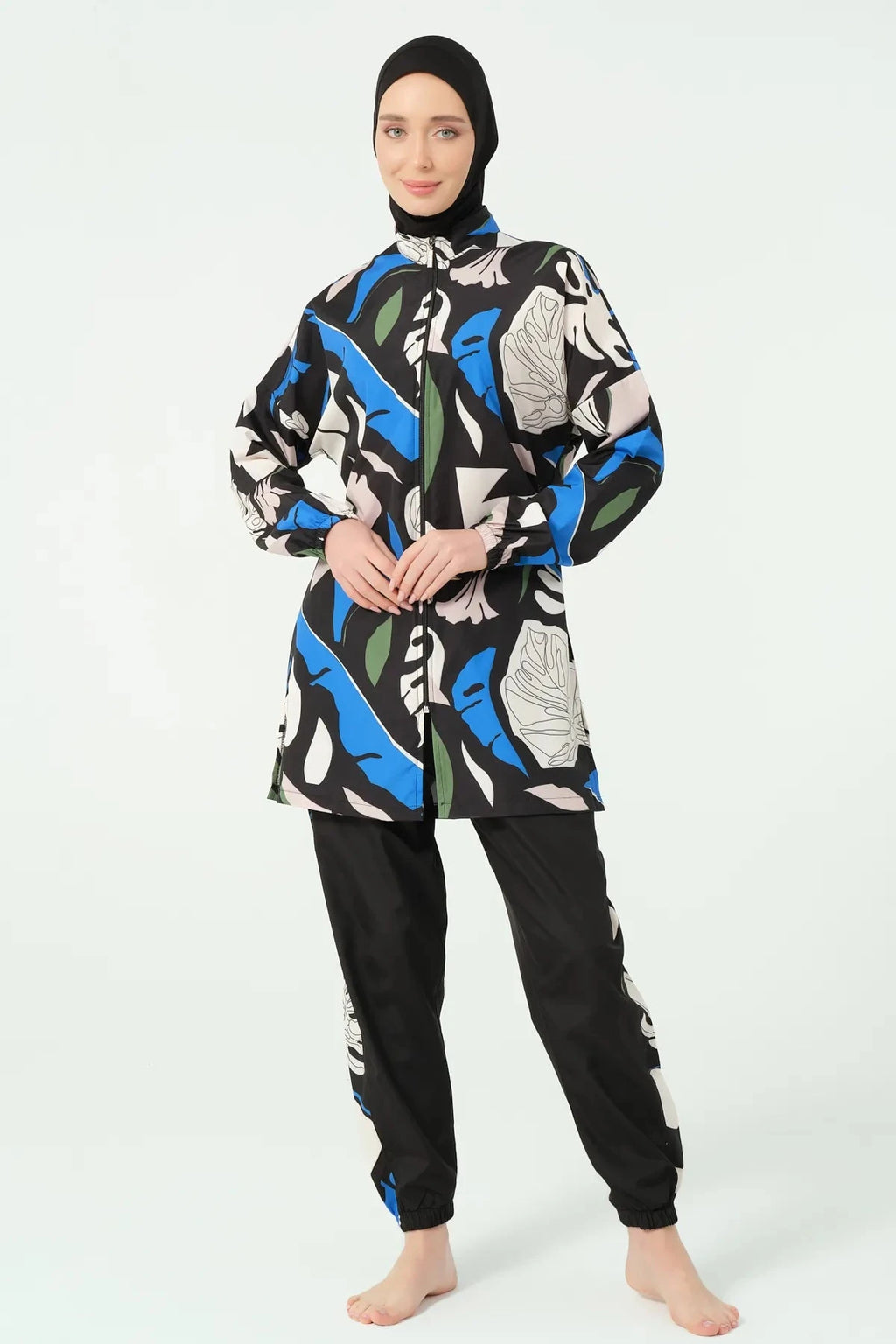 Woman wearing abstract print burkini set with black hijab, full body pose.