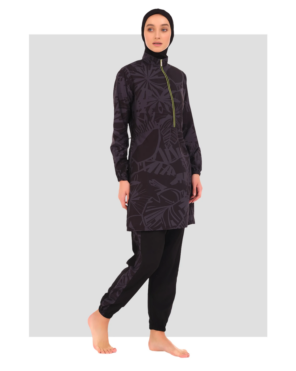 Model in dark patterned burkini with lime green zipper, side view.