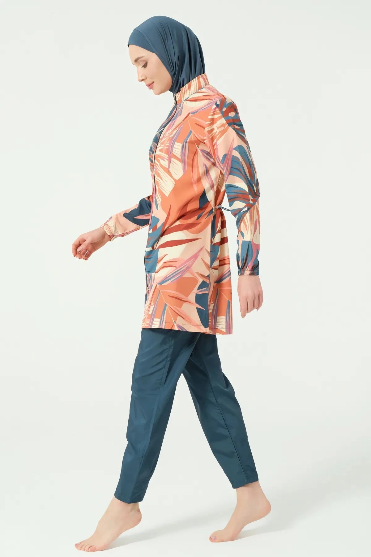 Model in petrol peach tropical burkini set walking side view.