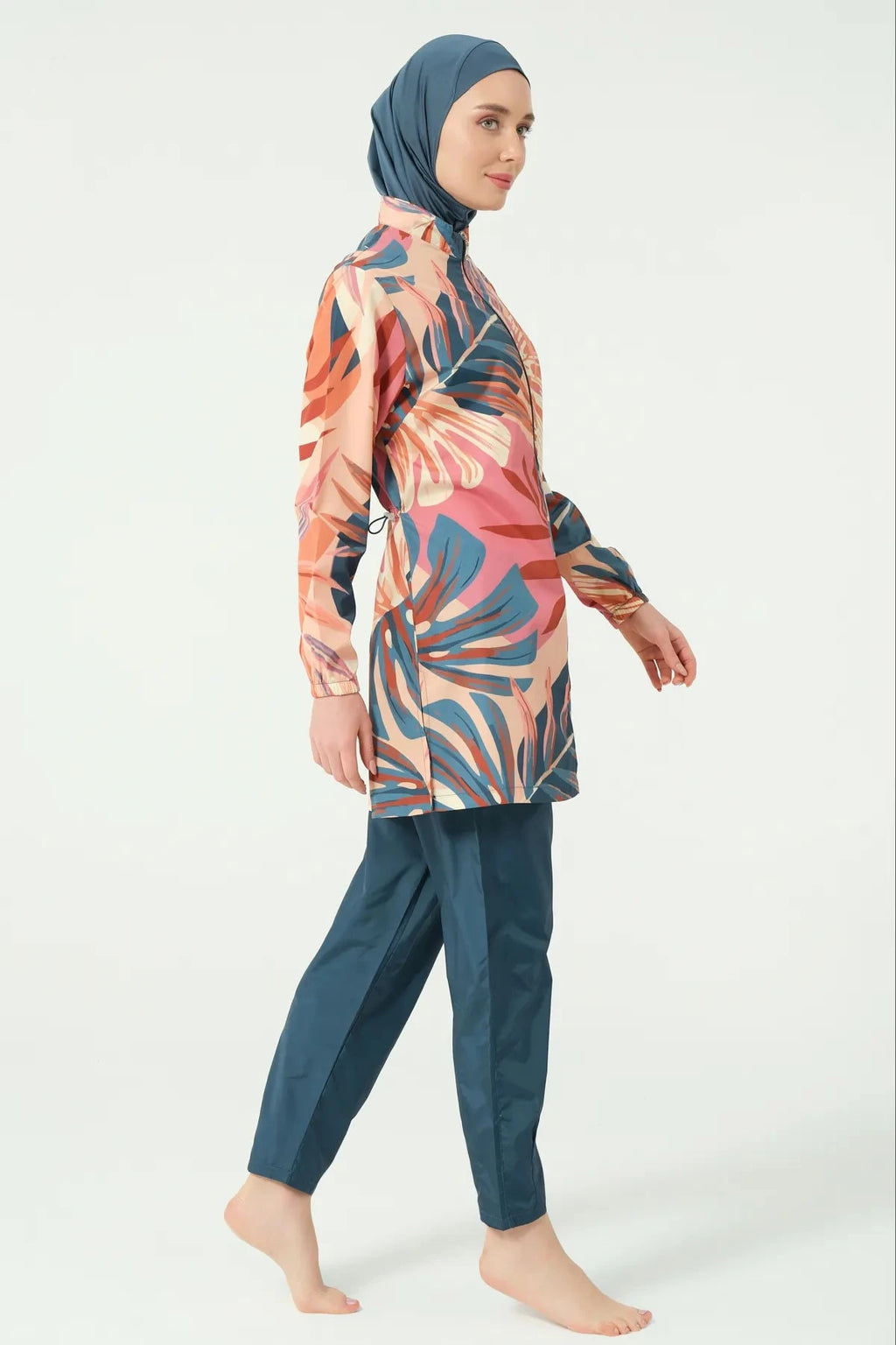 Model in petrol peach tropical burkini set standing side view.