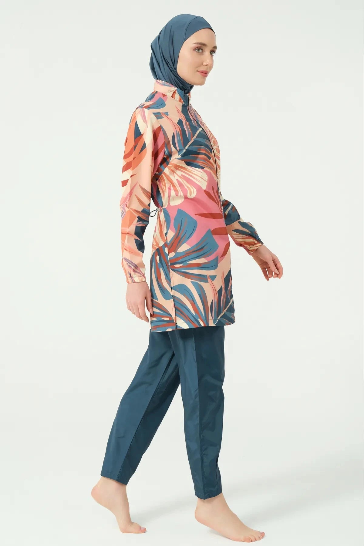 Model in petrol peach tropical burkini set standing side view.
