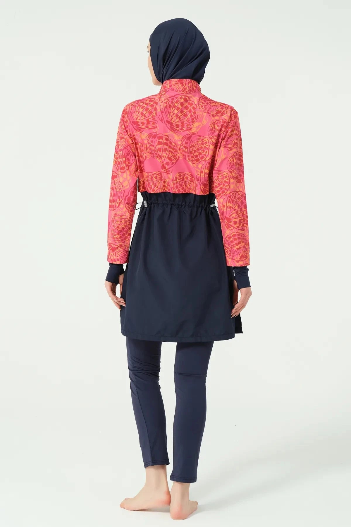 Back view of woman wearing navy and coral tropical print burkini.